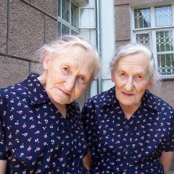 75-year old identical twins wearing identical dresses. 75-year old identical twins wearing identical dresses.