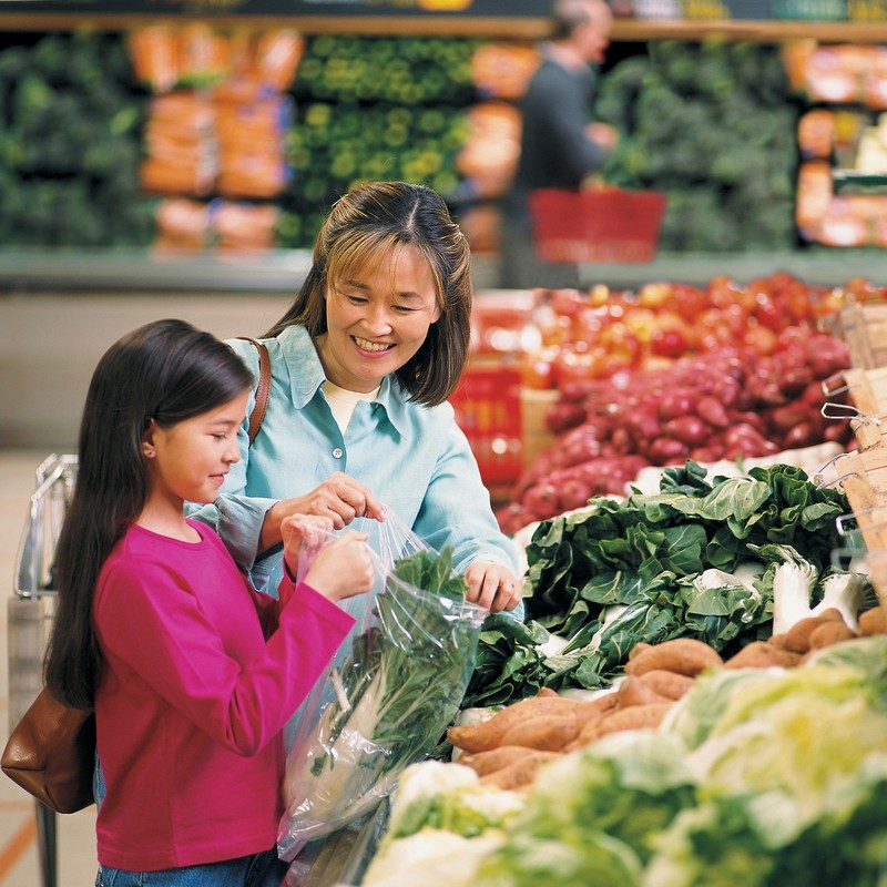 A mother and daughter shopping for vegetables at the supermarket. A mother and daughter shopping for vegetables at the supermarket.