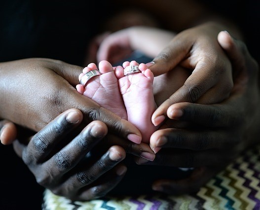 The hands of a mother and father cupping the tiny feet of a very small baby. The hands of a mother and father cupping the tiny feet of a very small baby.