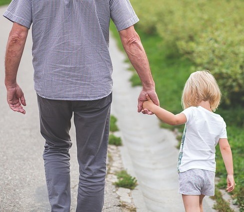A father and his small daughter walk along the road holding hands. A father and his small daughter walk along the road holding hands.