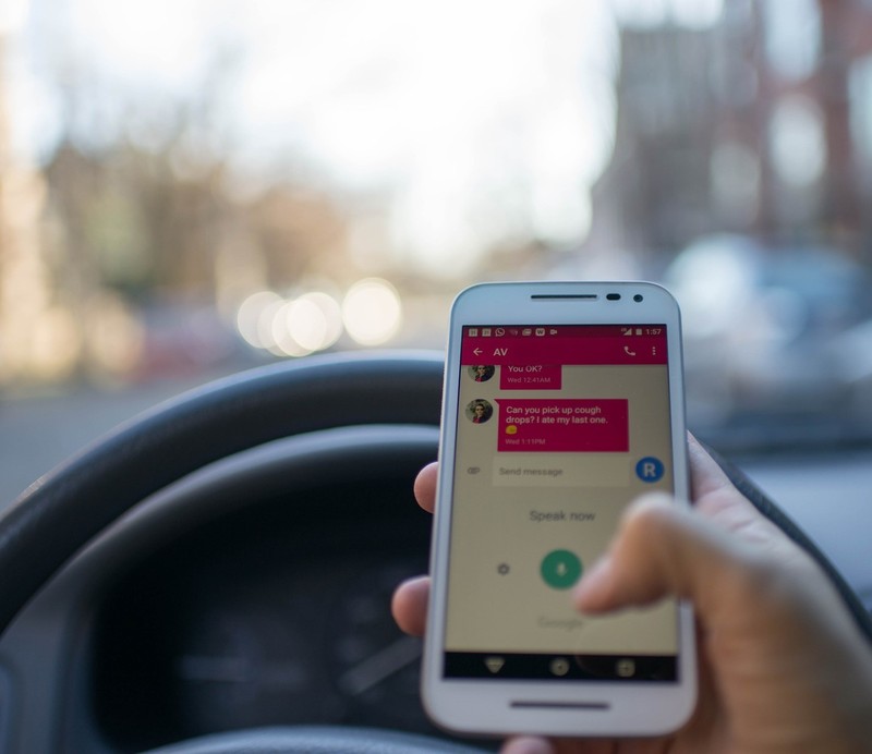 Image shows the point of view of a driver as she texts while behind the wheel. Image shows the point of view of a driver as she texts while behind the wheel.