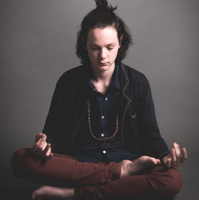 A young man sits in the lotus position meditating. A young man sits in the lotus position meditating.