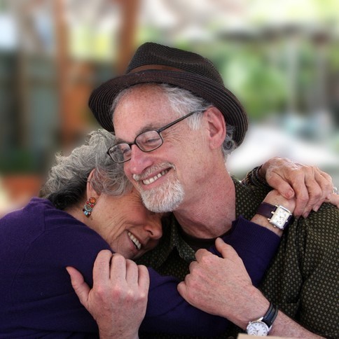 A grey-haired couple share an affectionate hug. A grey-haired couple share an affectionate hug.