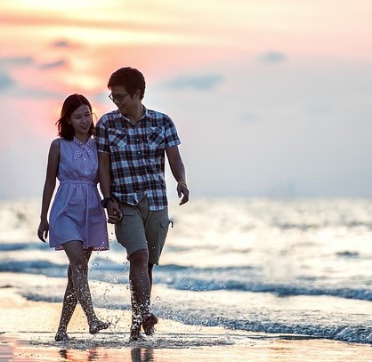 A young couple walk down the beach at sunset hand in hand. A young couple walk down the beach at sunset hand in hand.