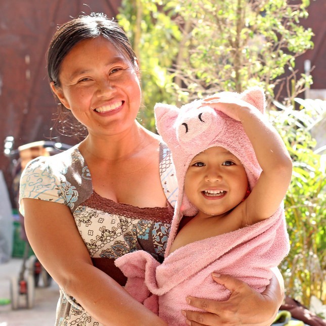 A smiling mother holds her happy toddler in a towel after a bath. A smiling mother holds her happy toddler in a towel after a bath.
