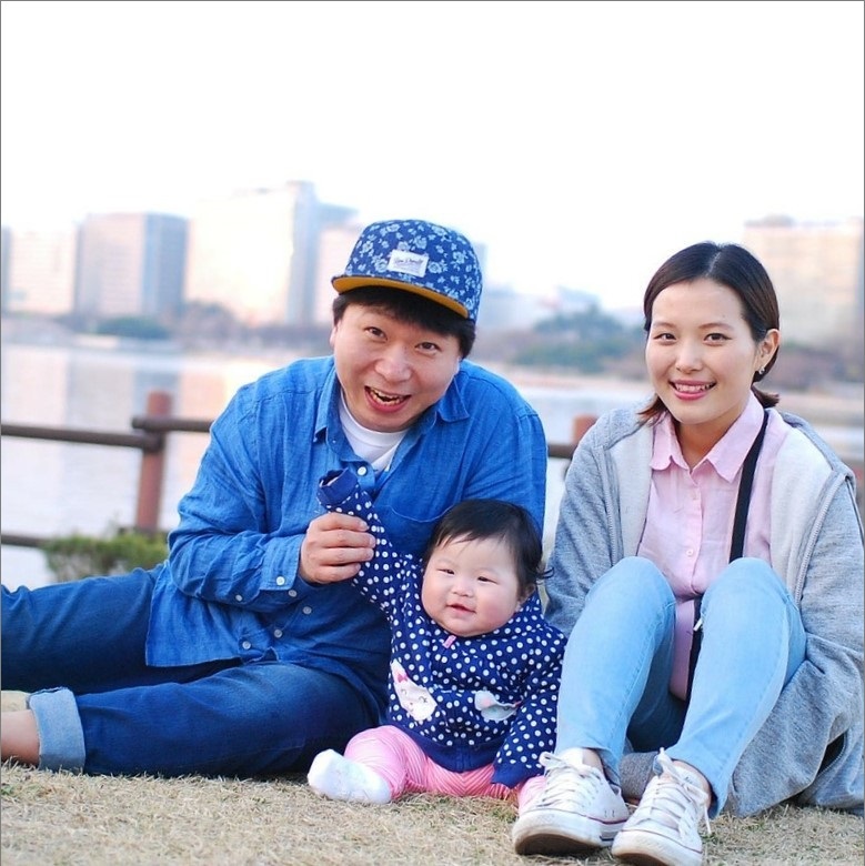A young mother and father sit with their infant in a park. A young mother and father sit with their infant in a park.