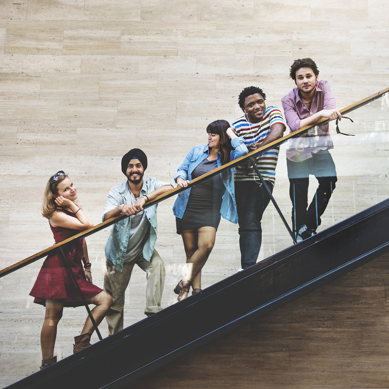 A group of young adult friends stand together on a staircase. A group of young adult friends stand together on a staircase.