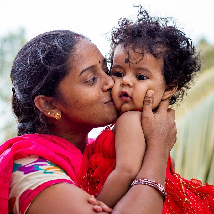 A mother looks lovingly at her son as she holds him in her arms and kisses him on the cheek. A mother looks lovingly at her son as she holds him in her arms and kisses him on the cheek.