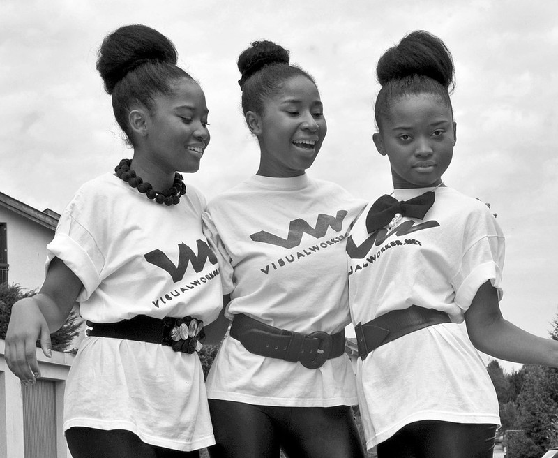A group of teen girls with matching shirts and hair styles pose together with their arms around one another. A group of teen girls with matching shirts and hair styles pose together with their arms around one another.