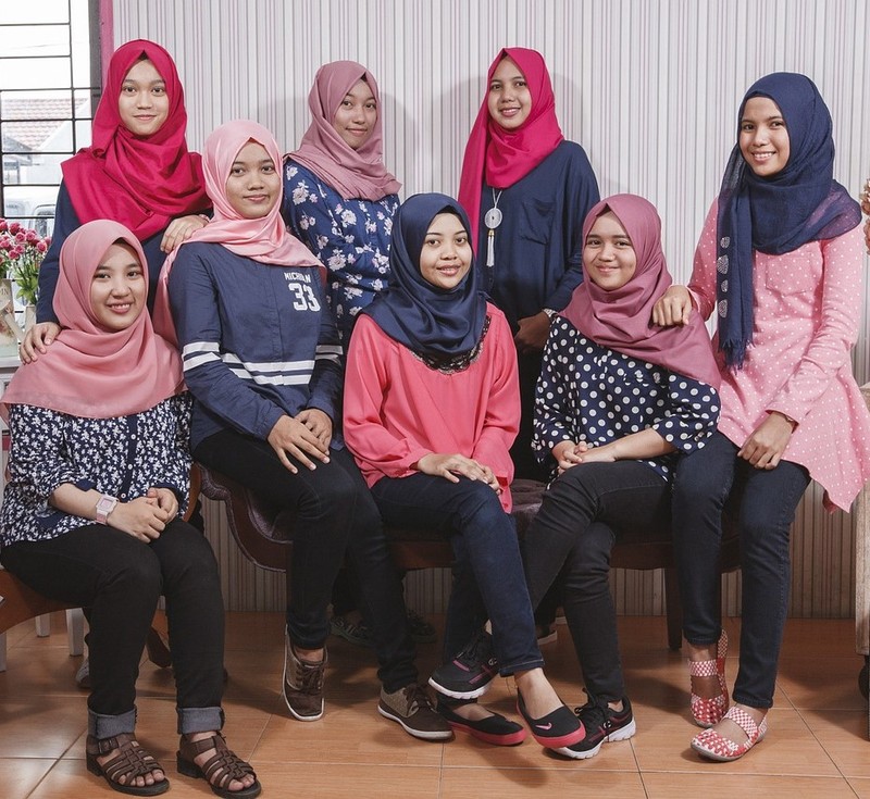 A group of Malaysian teen girls pose for a photo wearing casual clothing and traditional head scarves. A group of Malaysian teen girls pose for a photo wearing casual clothing and traditional head scarves.