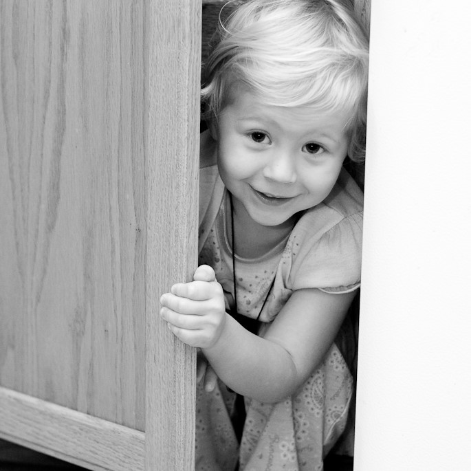 A young girl smiles as she peeks out from a hiding place. A young girl smiles as she peeks out from a hiding place.