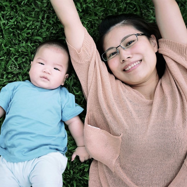 A mother and infant lie together on the grass. A mother and infant lie together on the grass.