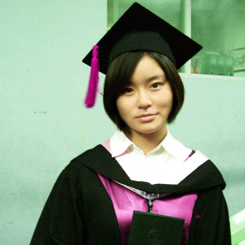 An East Asian woman dressed in a graduation cap and gown wears a neutral or subdued expression. An East Asian woman dressed in a graduation cap and gown wears a neutral or subdued expression.