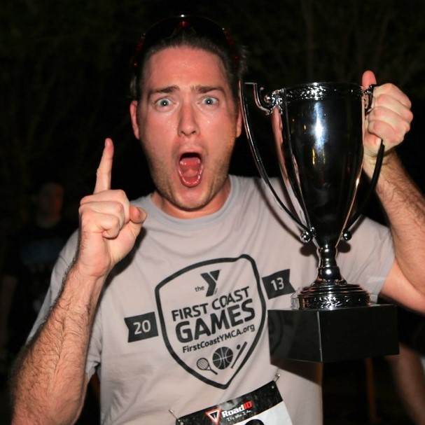 A European-American man celebrates as he holds a trophy he's won for winning a race. A European-American man celebrates as he holds a trophy he's won for winning a race.