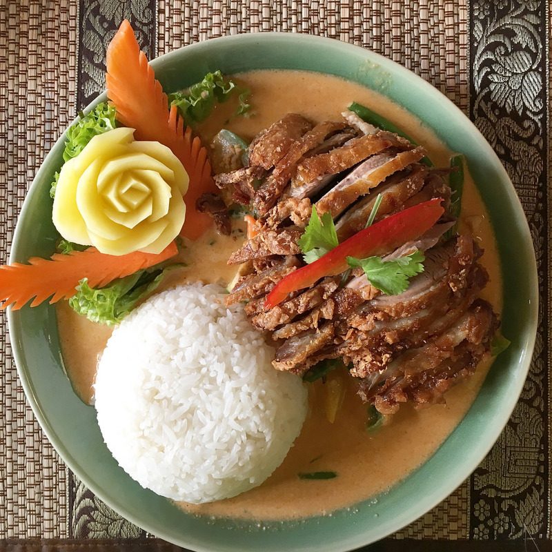 A chicken and rice meal is beautifully arranged on a plate. A chicken and rice meal is beautifully arranged on a plate.
