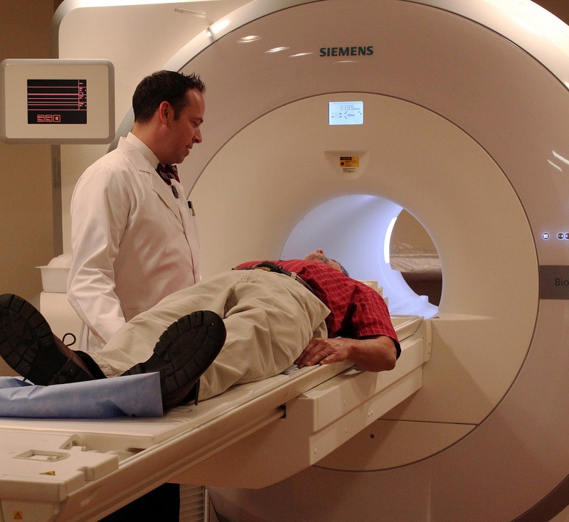 A doctor speaks to a patient who is lying on an fMRI table before undergoing a scan. A doctor speaks to a patient who is lying on an fMRI table before undergoing a scan.