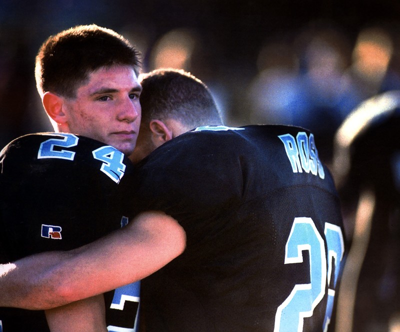 Football players embrace in disappointment after losing a game. Football players embrace in disappointment after losing a game.