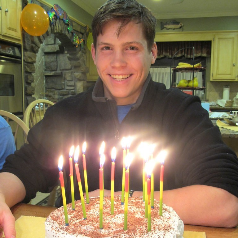 A man smiles as he prepares to blow out the candles on a birthday cake. A man smiles as he prepares to blow out the candles on a birthday cake.