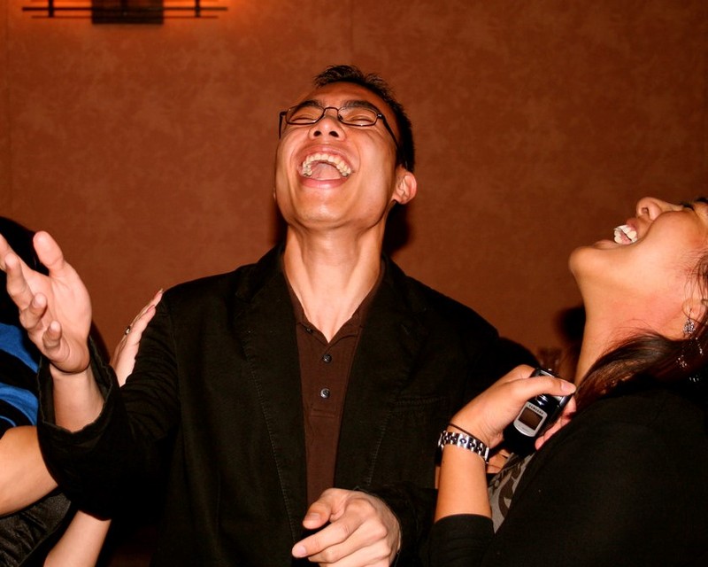 A man and woman both throw their heads back in laughter. A man and woman both throw their heads back in laughter.