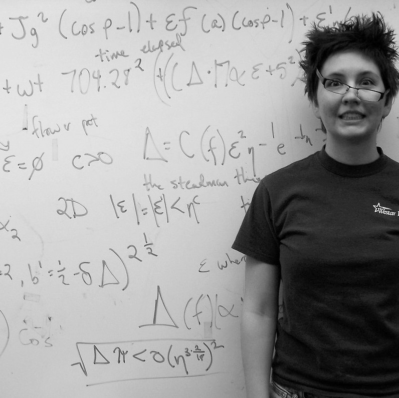 A woman stands triumphant but slightly disheveled after solving a complicated math problem on the whiteboard. A woman stands triumphant but slightly disheveled after solving a complicated math problem on the whiteboard.