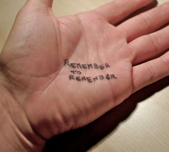 A note is written on a man's hand which says, "remember to remember". A note is written on a man's hand which says, "remember to remember".