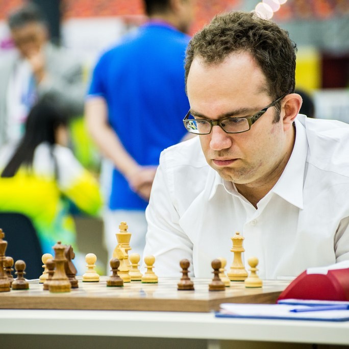 A man sits hunched over looking at the pieces on a chessboard with an expression of deep concentration on his face. A man sits hunched over looking at the pieces on a chessboard with an expression of deep concentration on his face.
