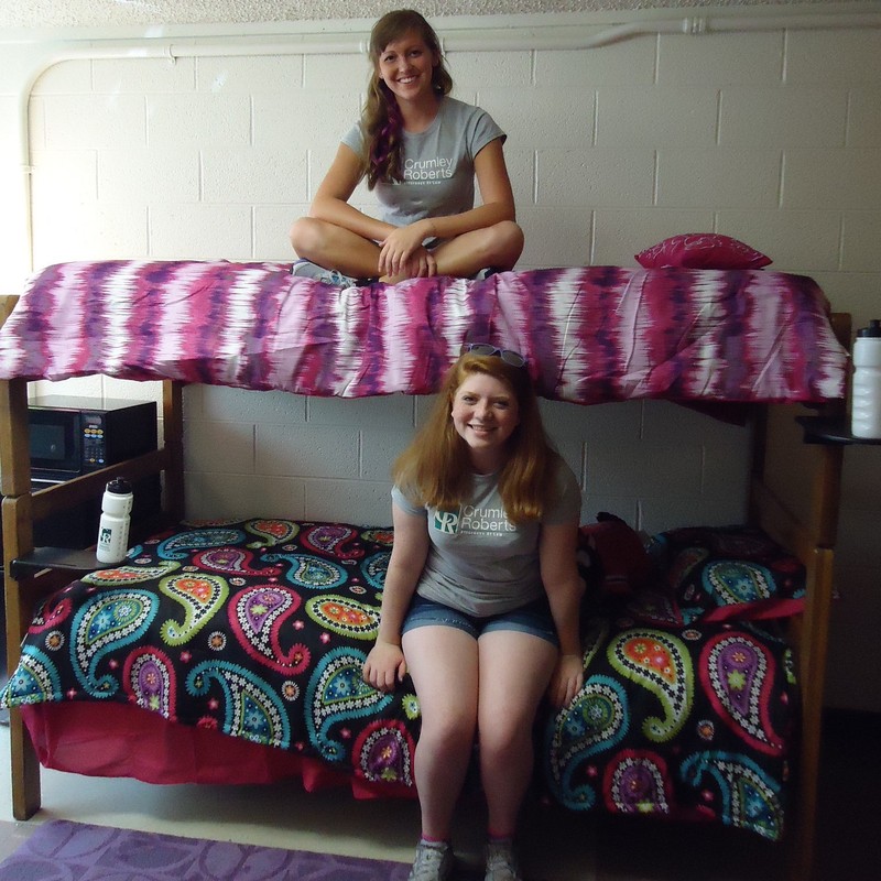 Two college students sit on bunk beds in a very clean and orderly dorm room. Two college students sit on bunk beds in a very clean and orderly dorm room.
