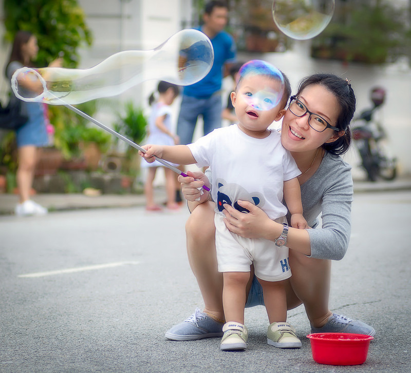 A mother helps her young son use a bubble wand. A mother helps her young son use a bubble wand.