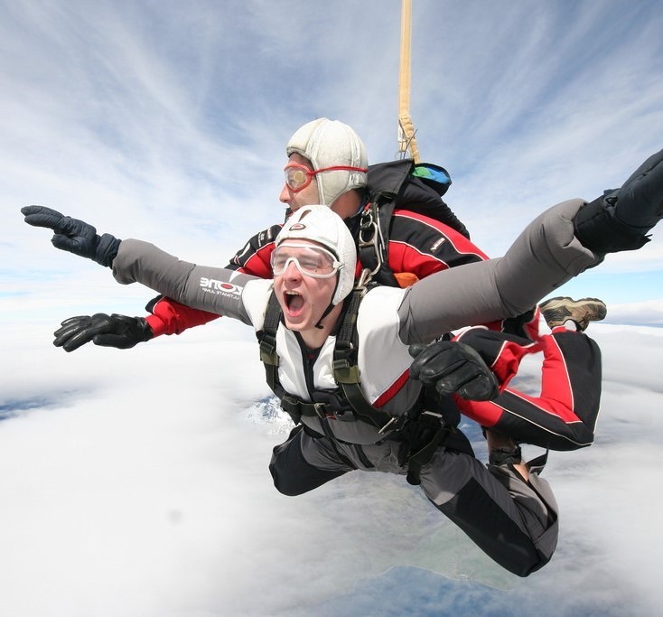 A man yells with excitement during a tandem skydive. A man yells with excitement during a tandem skydive.