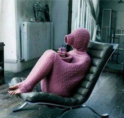 A person sits on a chair almost completely hidden inside a long sweater. A person sits on a chair almost completely hidden inside a long sweater.