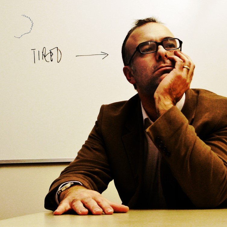 A tired man props his head on his hand. A tired man props his head on his hand.