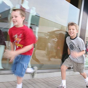 Two young boys sprint along the sidewalk. Two young boys sprint along the sidewalk.
