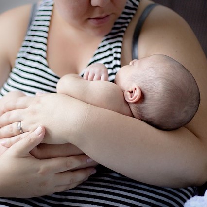 A young mother holds an infant in her arms. A young mother holds an infant in her arms.