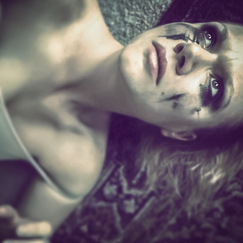 A distraught looking woman lies on the floor with makeup smeared across her face. A distraught looking woman lies on the floor with makeup smeared across her face.