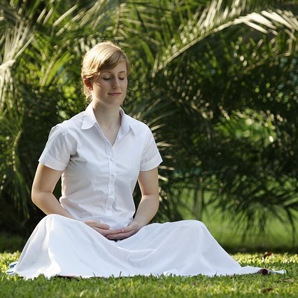 A woman sits in the grass meditating. A woman sits in the grass meditating.