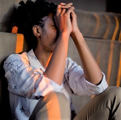 A woman sits on the floor and covers her face in sadness. A woman sits on the floor and covers her face in sadness.