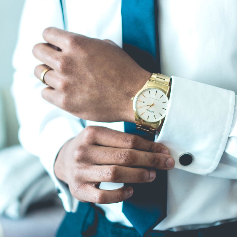 A man dressed in business attire and an expensive watch adjusts his cufflinks. A man dressed in business attire and an expensive watch adjusts his cufflinks.