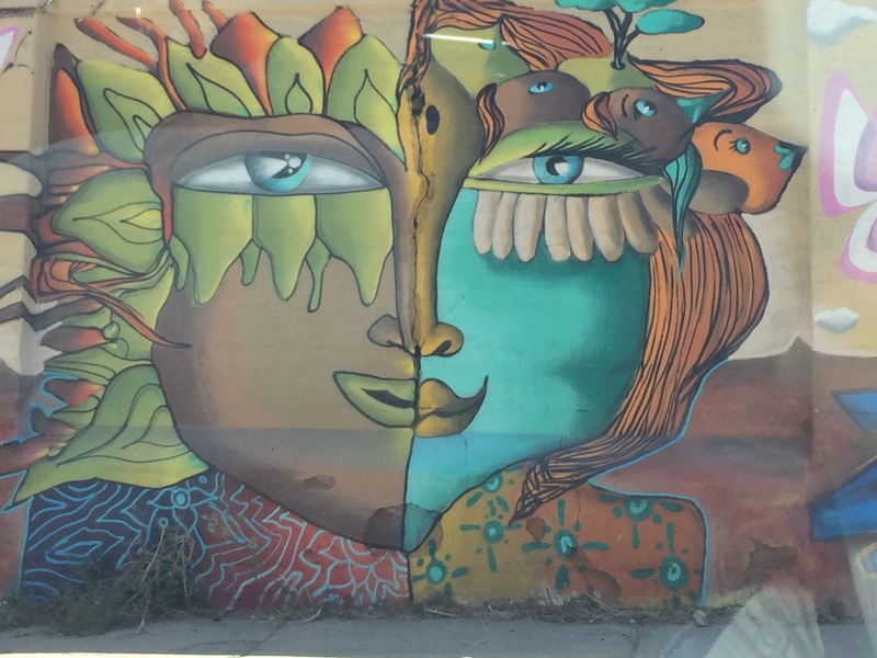 A picture of a face one half brown one half teal with half of the face having plants instead of hair, and the other half having faces and animals of varying kinds replacing the area where the hair should be. The eyes are blue but different shapes; the nose is split up into two colors – yellow and brown and the lips are split into two colors – green and yellow. A picture of a face one half brown one half teal with half of the face having plants instead of hair, and the other half having faces and animals of varying kinds replacing the area where the hair should be. The eyes are blue but different shapes; the nose is split up into two colors – yellow and brown and the lips are split into two colors – green and yellow.