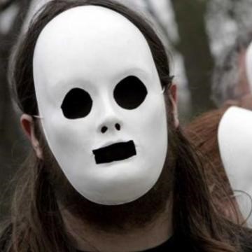 A man is seen wearing an expressionless white plaster mask with black eyes and mouth. A man is seen wearing an expressionless white plaster mask with black eyes and mouth.