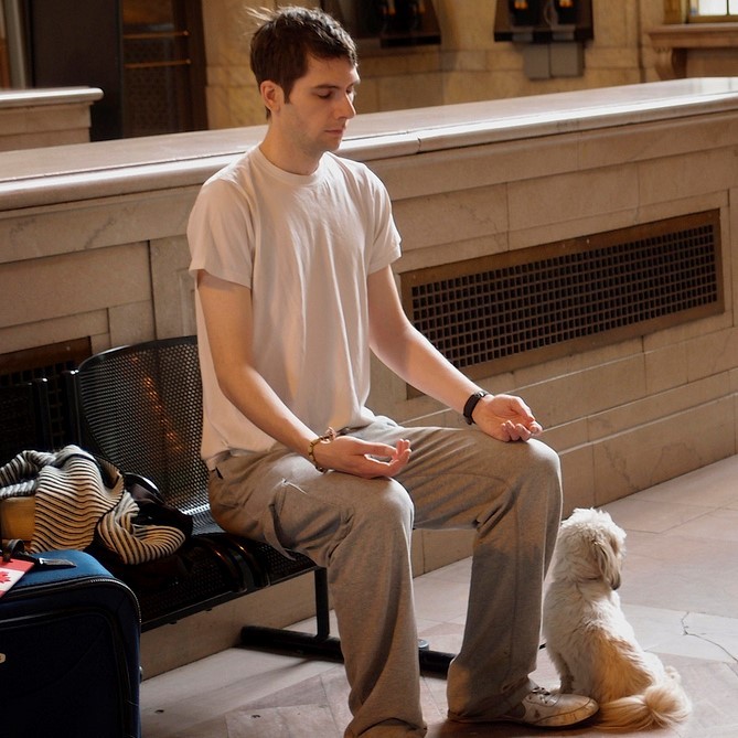 A young man meditates on a bench in a train station. A young man meditates on a bench in a train station.