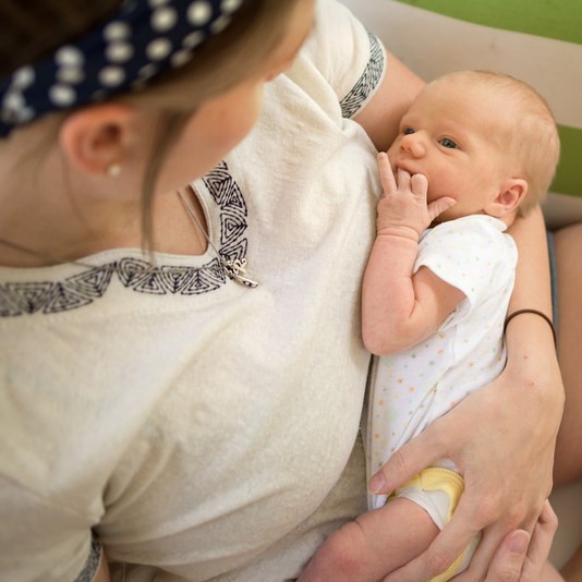 An infant looks up at its mother as she cradles the child in her arms. An infant looks up at its mother as she cradles the child in her arms.