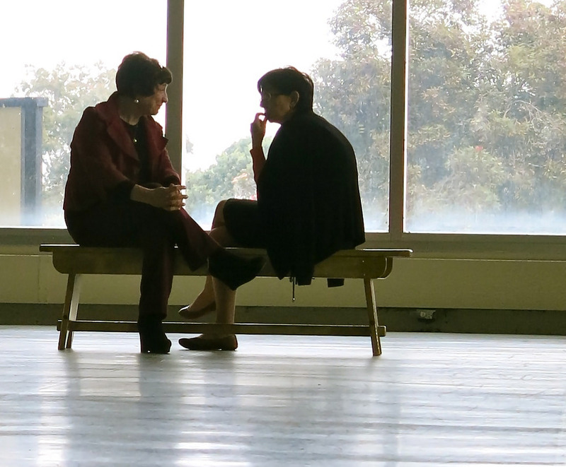 Two women sit having a quiet conversation in a public place. Two women sit having a quiet conversation in a public place.