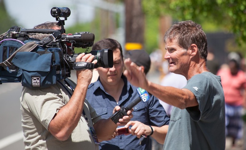 A man stands in front of a television camera and microphone as he describes an event he has witnessed. A man stands in front of a television camera and microphone as he describes an event he has witnessed.