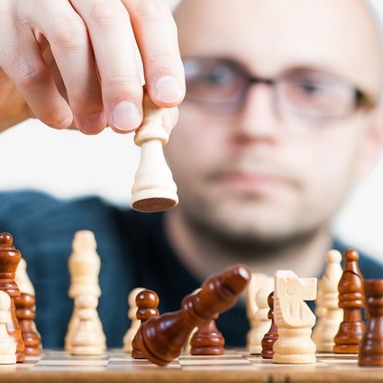 A man makes a chess move. A man makes a chess move.
