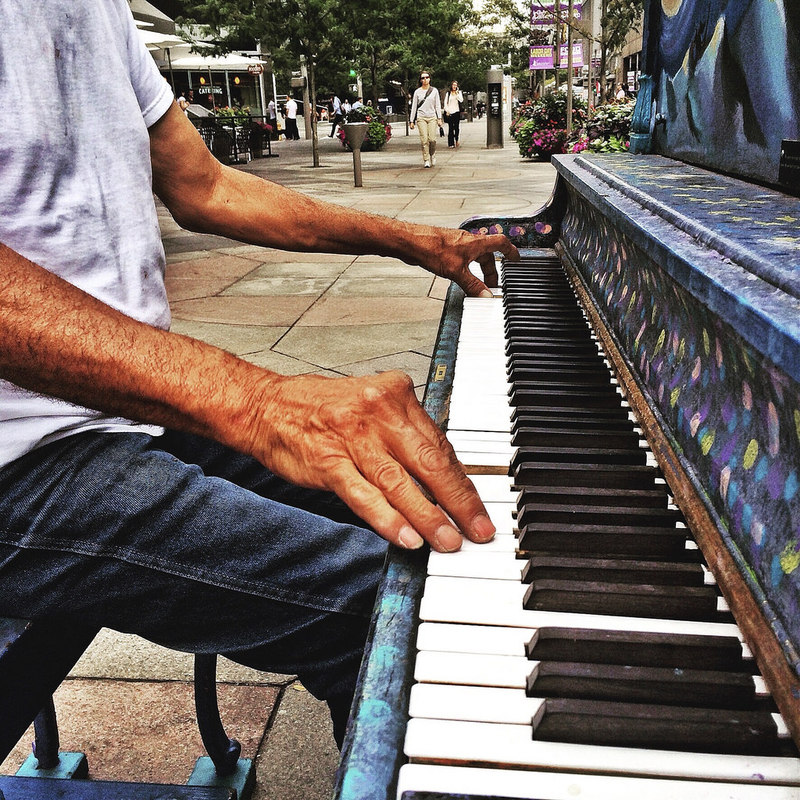 A man plays a piano on a sidewalk. A man plays a piano on a sidewalk.