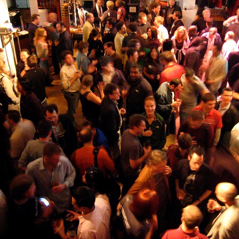 People stand and talk in groups of 3 or 4 during a party. People stand and talk in groups of 3 or 4 during a party.