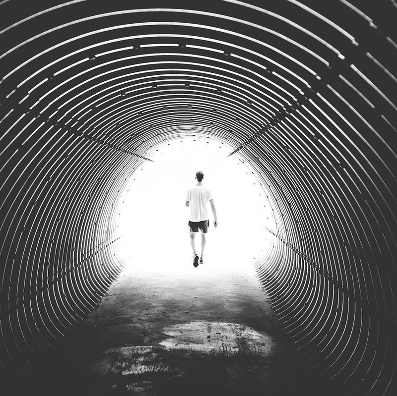 A man walks out of a dark tunnel into bright daylight. A man walks out of a dark tunnel into bright daylight.