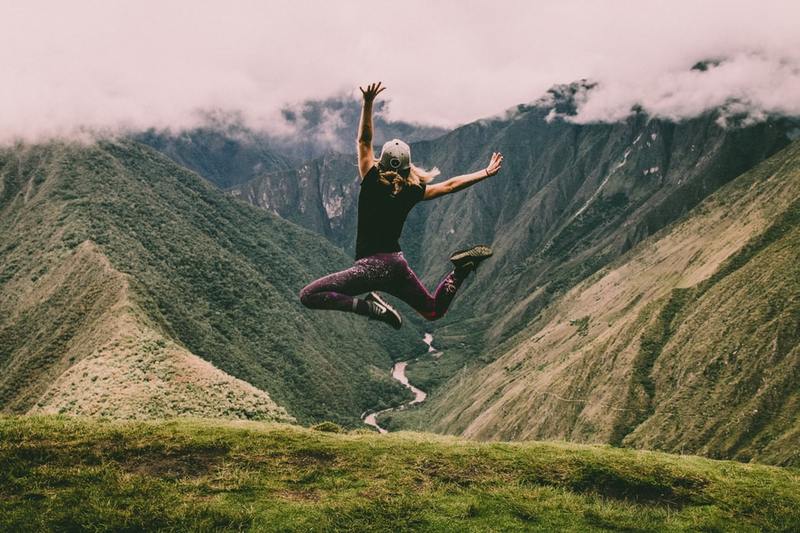 A person jumping up with hands and feet in the air on a mountaintop A person jumping up with hands and feet in the air on a mountaintop