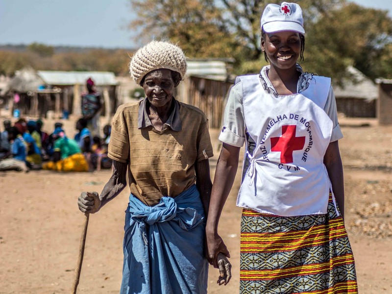 A Red Cross volunteer assists an elderly lady from Mozambique, where a food distribution was taking place. A Red Cross volunteer assists an elderly lady from Mozambique, where a food distribution was taking place.