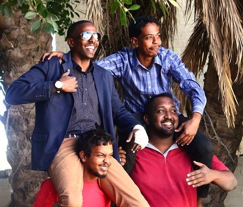 A happy group of young men pose for a photo. Two of them sit smiling on the shoulders of their friends below. A happy group of young men pose for a photo. Two of them sit smiling on the shoulders of their friends below.